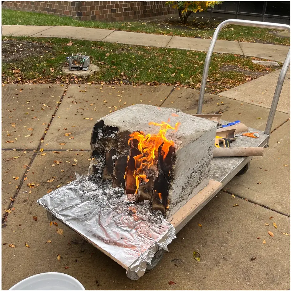 The concrete mockup with its cardboard formwork burning